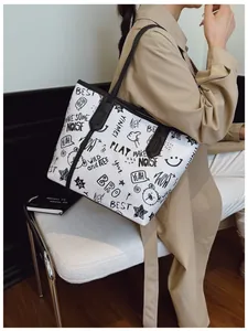 Detail of white tote bag with black street graffiti prints and long shoulder handles