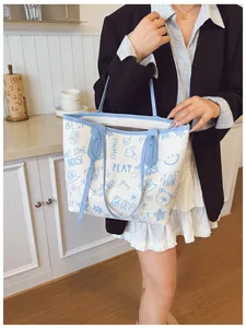Detail of large tote bag showing graffiti cartoon prints and sky blue shoulder straps