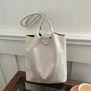 Sac seau minimaliste beige givré avec bandoulière tissée dans un cadre de café chic