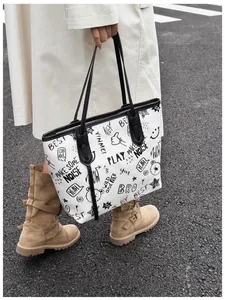 Detail of white graffiti tote bag featuring street style prints and black handles