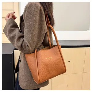Nahaufnahme einer braunen Leder-Tote-Bag mit gelbem Logo und langem Schultergurt
