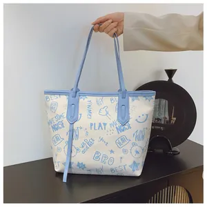 Close-up of a white tote bag with light blue trim and artistic graffiti pattern prints
