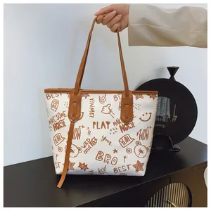 Detail of large tote bag showing graffiti print patterns and brown leather shoulder straps