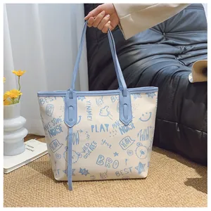 Detail of large tote bag with cute blue cartoon prints and PU leather handles held by hand