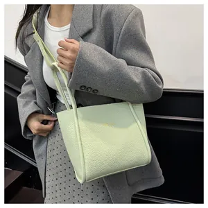 Detail der mintgrünen Tote Bag aus Leder mit Litschimuster und Goldschrift an einem Model