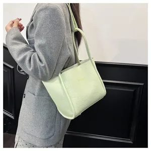 Detailansicht der mintgrünen Tote Bag aus Leder mit Goldprägung auf einem Wollmantel