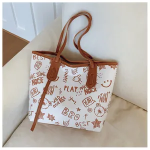 Macro detail of graffiti print tote bag featuring brown leather trim and bear patterns