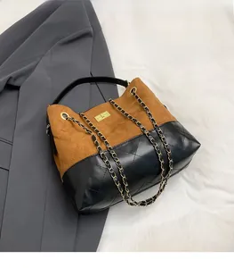 Detailed view of brown faux suede tote bag featuring diamond quilting and gold chain strap