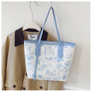 Detailed view of the street graffiti print and light blue trim on the white tote bag