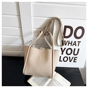 Nahaufnahme der beigen Beuteltasche aus Leder mit Lychee-Muster und goldenem Schriftzug