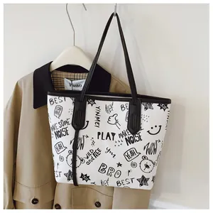 Detail of white tote bag featuring black cartoon graffiti and durable shoulder straps