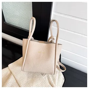 Detailansicht der beigen Tasche mit Lychee-Struktur, Goldaufdruck und Schultergurt