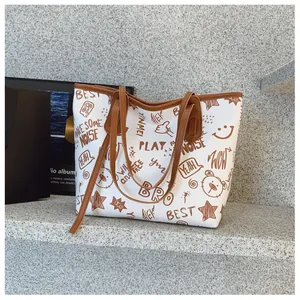 Detail of white tote bag with cute cartoon graffiti patterns and brown leather handles