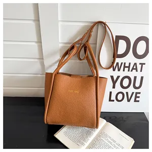 Detailansicht der braunen Handtasche aus Leder mit Narbung und Goldaufschrift