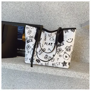 Detail shot of large tote bag featuring artistic black graffiti prints and slim straps