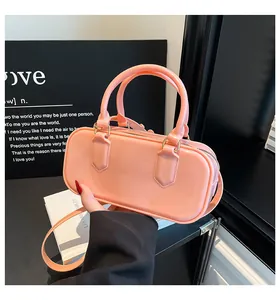 Detail of a bright orange glossy handbag with handles and a zipper on a minimalist background