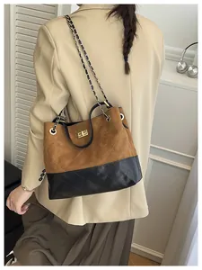 Detail of a two-tone crossbody bag featuring brown suede and black quilted leather