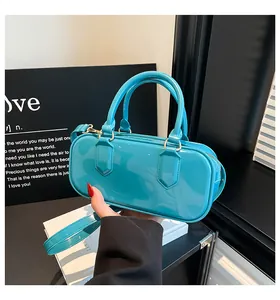 Detailed view of the glossy teal patent leather cylindrical handbag with top zipper closure