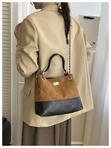 Close-up of a two-tone suede and quilted leather shoulder bag with gold chain strap