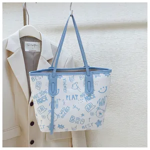 Detail of large tote bag with blue cartoon graffiti prints and durable leather handles