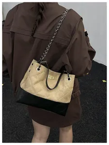 Detail of hobo bag featuring beige suede, black leather quilting and chain strap