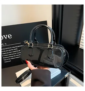 Detailed view of black patent leather handbag with glossy finish and gold hardware