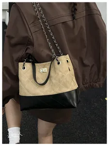 Detail of contrast stitch tote bag with gold metal clasp and chain strap on shoulder