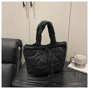 Close-up of black heart-quilted dumpling bag featuring woven drawstring details