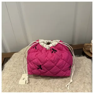 Detail of fuchsia quilted drawstring bag with bow embroidery and 'egg' woven label