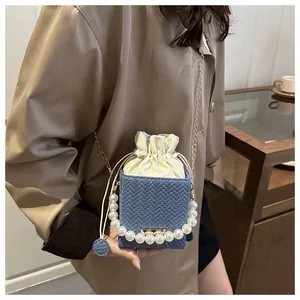 Detail of blue woven mini bucket bag with white pearl handle and satin drawstring closure