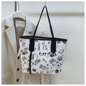 Detail of white tote bag with black graffiti cartoon prints and slim shoulder straps
