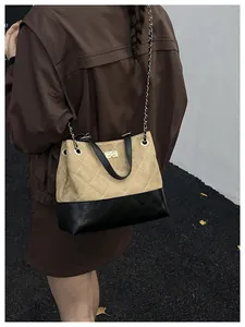 Detail of contrast stitching, diamond quilted texture and golden chain on shoulder bag