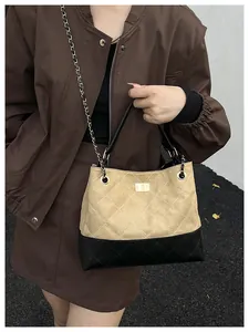 Detail of contrast stitch quilted handbag with gold twist lock and chain strap on model