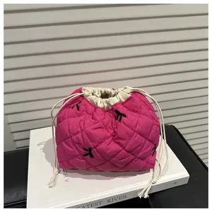 Detail of pink quilted drawstring makeup bag with black bow embroidery on a book