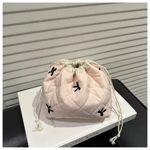 Detailed shot of pink quilted drawstring storage bag with black bow embroidery