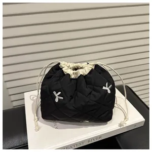 Close-up of black quilted drawstring bag with silver bow accents and contrast trim