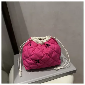 Detail of pink quilted drawstring makeup bag with embroidered black bow patterns