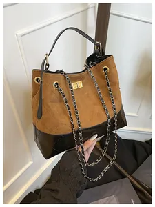 Close-up of contrast suede and quilted leather panels with gold chain strap on retro bag