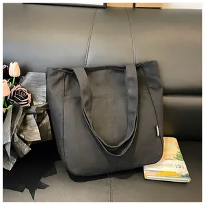 Detailopname van een grote zwarte canvas shopper met de stoftextuur en het zijlabel