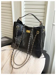 Detail of black quilted leather tote bag with gold chain strap and metal swivel lock