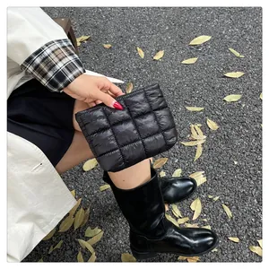 Detail einer schwarzen gesteppten Puffer-Clutch aus wasserfestem Nylon, gehalten von Model