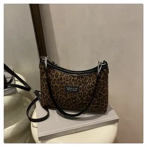 Dettaglio della borsa tote leopardata con finiture in pelle nera e patch logo