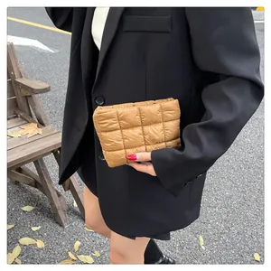 Detailaufnahme der khakifarbenen gesteppten Puffer-Clutch vor einem Streetstyle-Hintergrund