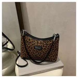 Dettaglio della borsa tote leopardata con cinturini in pelle nera ed etichetta logo