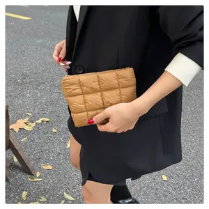 Braune gesteppte Clutch aus Nylon im modischen Puffer-Stil im Freien präsentiert