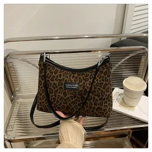 Dettaglio della borsa tote leopardata con cinturini in pelle nera su scaffale di metallo