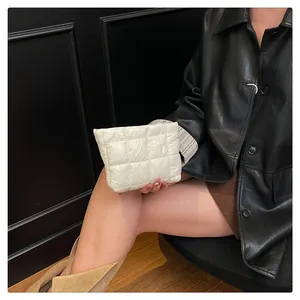 Detail einer weißen Puffer-Tasche mit Steppmuster, gehalten von Model in schwarzem Leder
