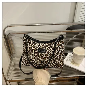 Dettaglio della borsa tote leopardata con forma a mezzaluna e tracolla nera fine