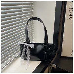 Detail of black glossy shoulder bag with white lace bow and silver metal buckle