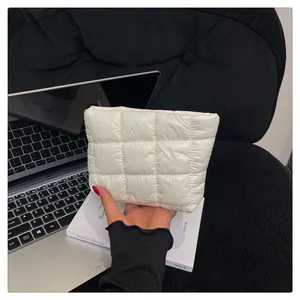 Nahaufnahme einer weißen gesteppten Clutch-Tasche, gehalten in einem Büro-Ambiente